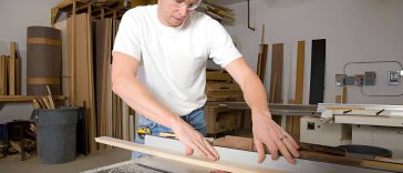 a man using a cross cut sled in the shop