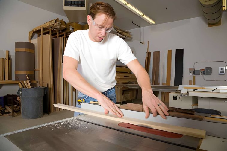 a man using a cross cut sled in the shop