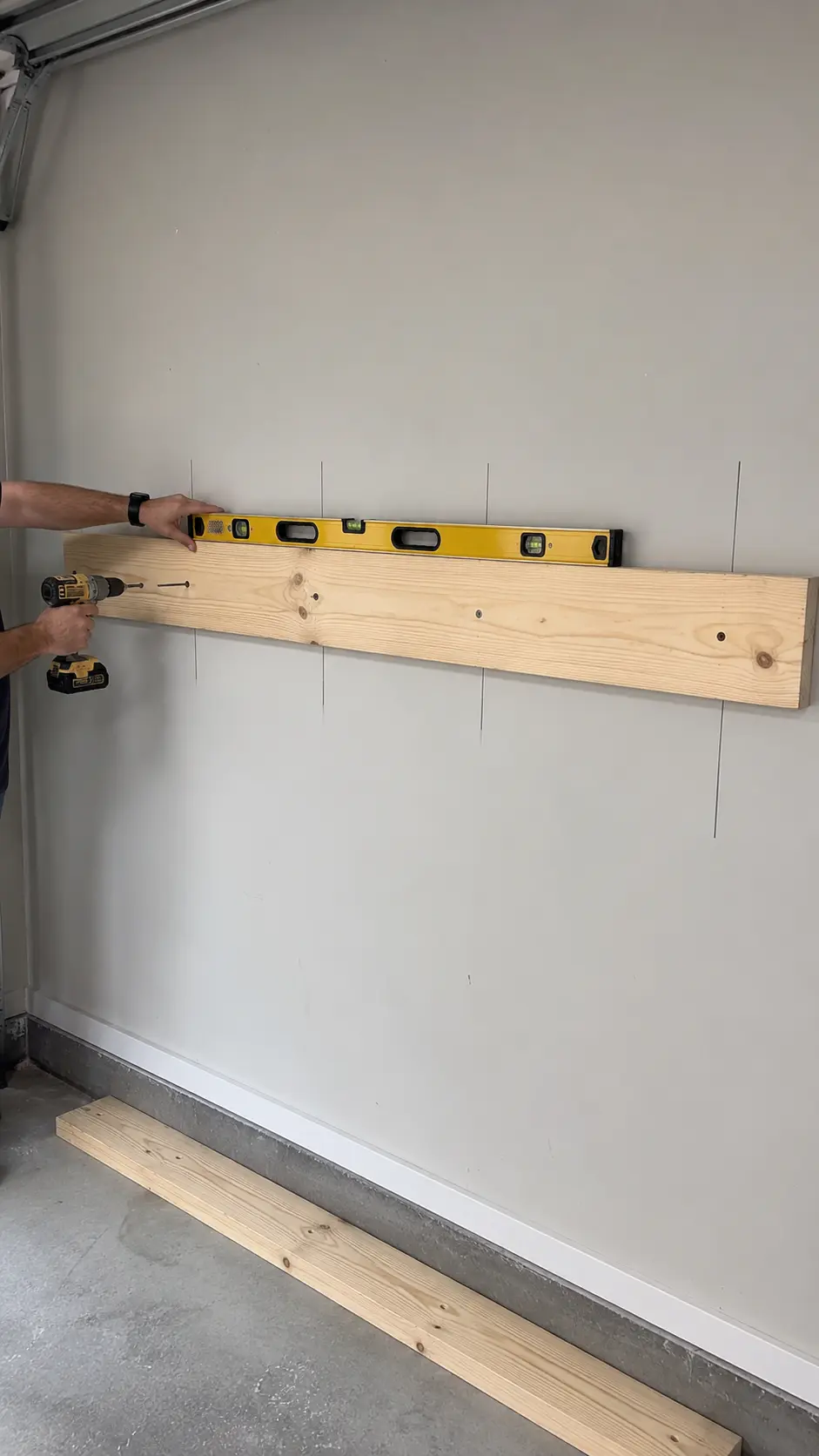 Upper 2 by 6 ledger being leveled and fastened into marked wall studs