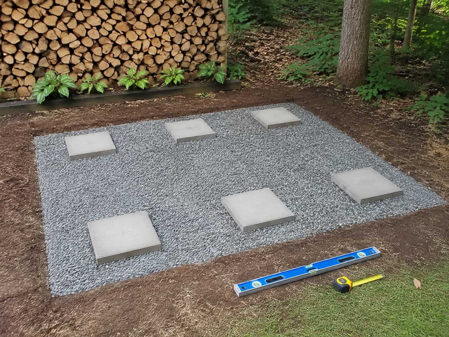 Level gravel foundation with six concrete pavers for a DIY firewood rack