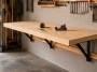 Completed DIY folding wall-mounted workbench open in a small garage workshop