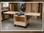 Finished mobile miter saw stand with birch plywood cabinet, open folding wings and locking casters in a garage workshop