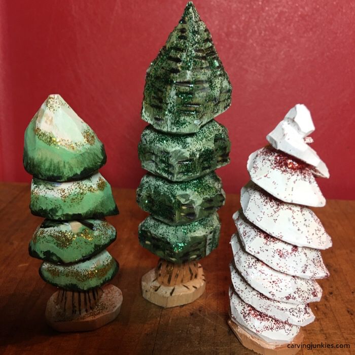 Three painted miniature wooden Christmas trees with different carved textures