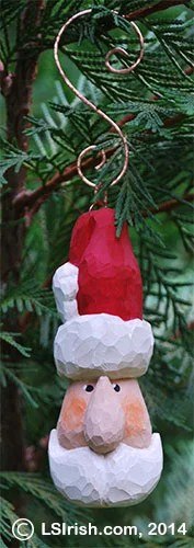 Lora Irish carved Santa face ornament hanging from a Christmas tree