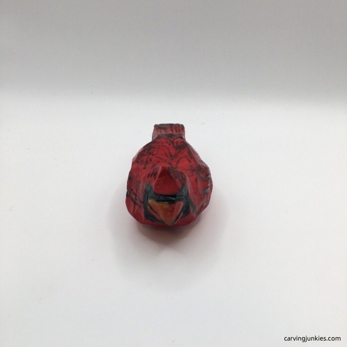 Red wooden cardinal carving mounted on a natural branch
