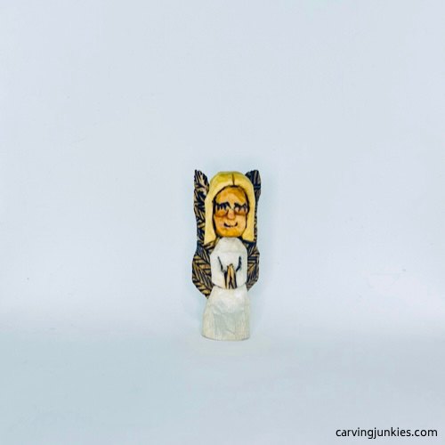 Small carved wooden angel with folded hands and pale dress