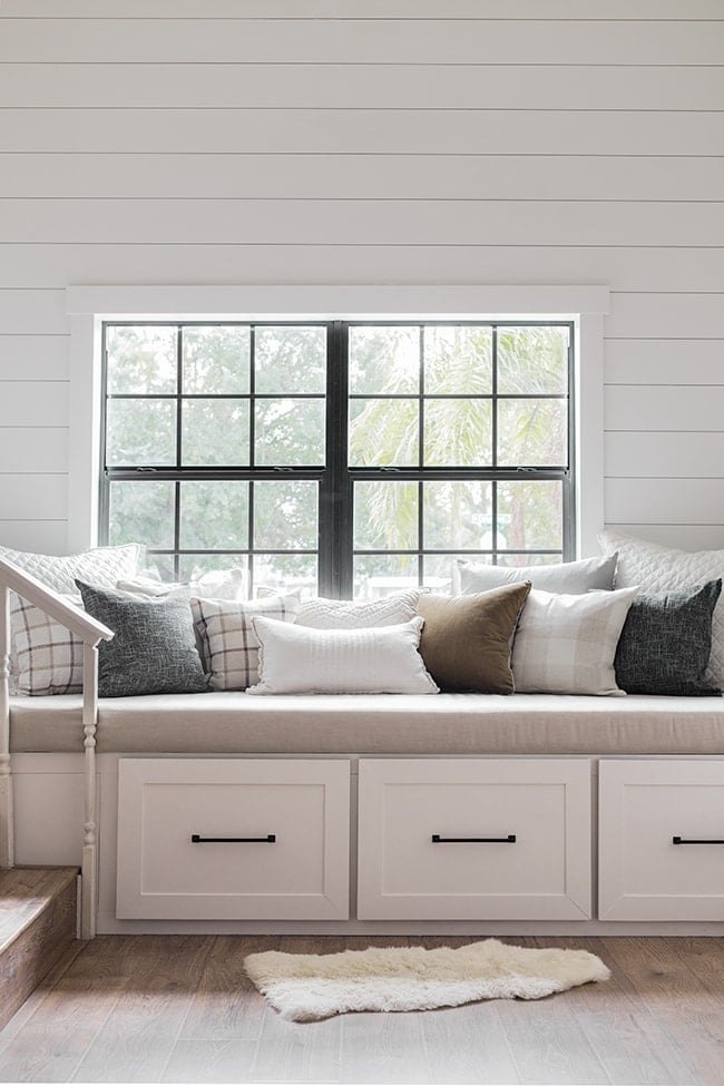 White built-in reading bench with three drawers below a window