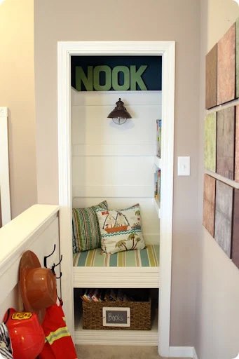 Small closet book nook with a cushioned bench and shelves