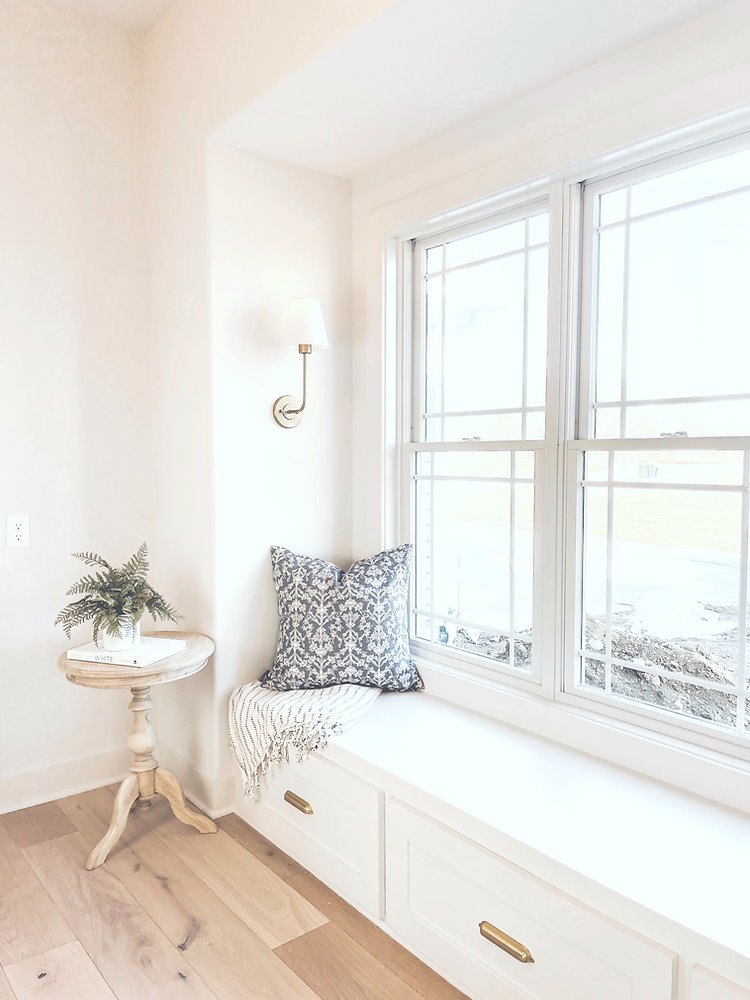 White window seat with paneled drawers and reading cushions