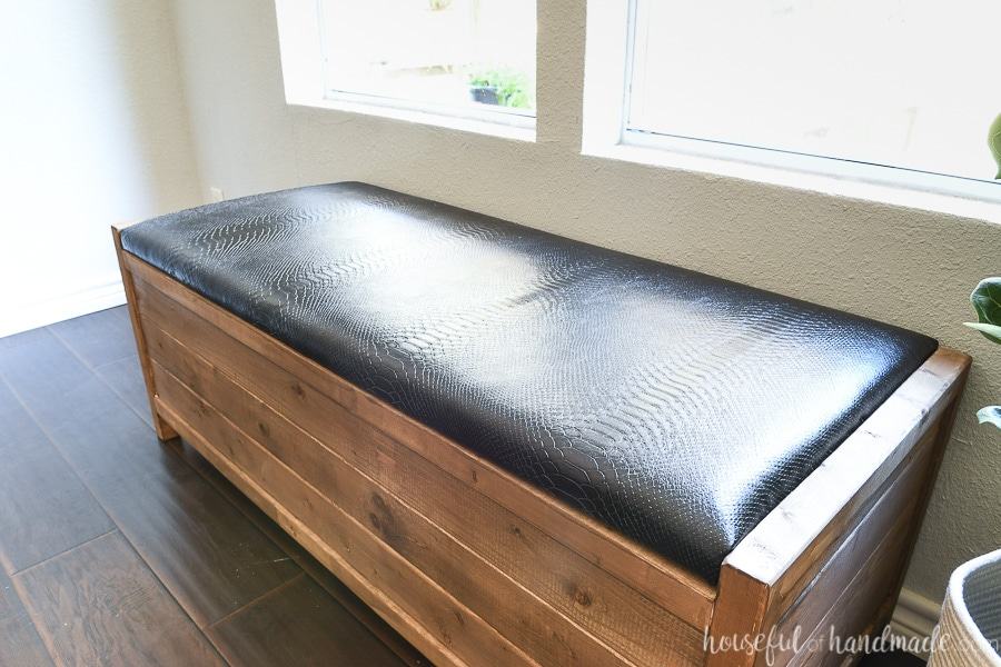 Freestanding wooden storage bench with a black upholstered lid