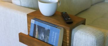 Wooden sofa arm tray with a book pocket on a pale sofa