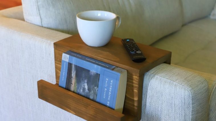 Wooden sofa arm tray with a book pocket on a pale sofa