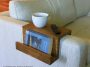 Wooden sofa arm tray with a book pocket on a pale sofa