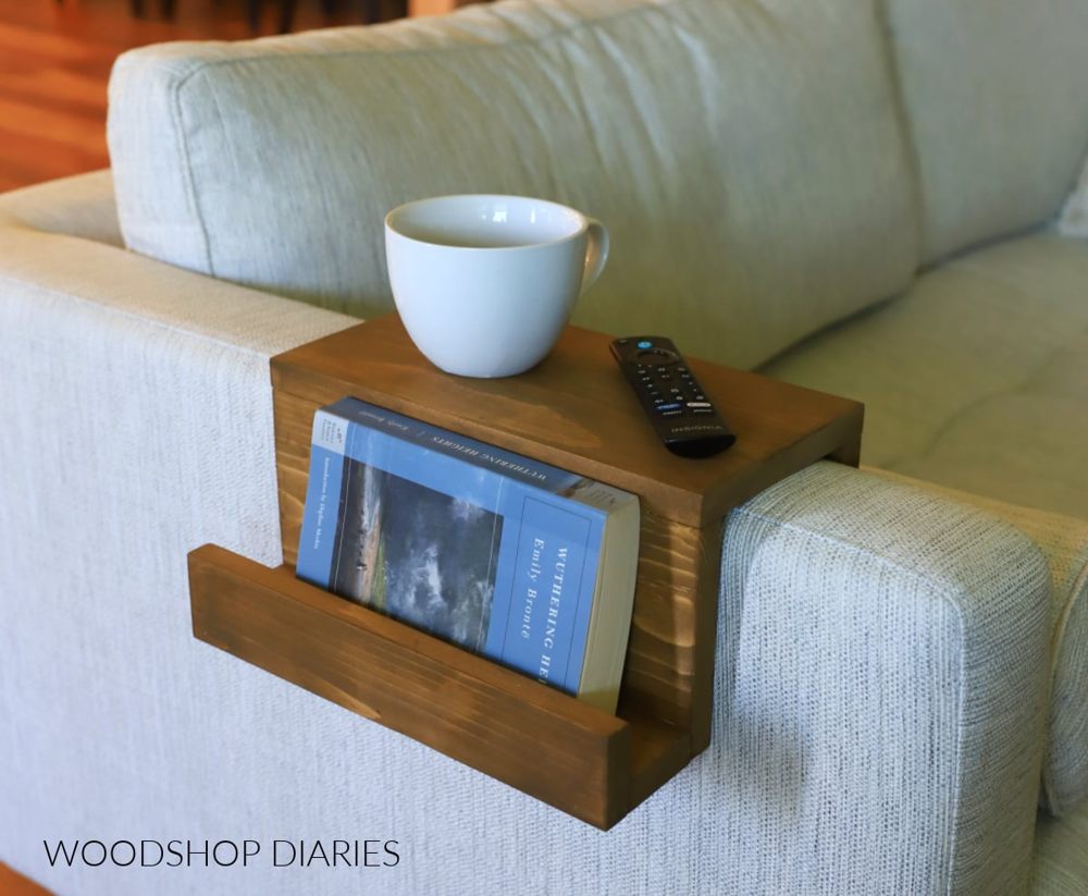 Wooden sofa arm tray with a book pocket on a pale sofa