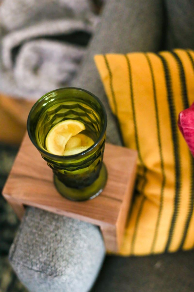 Close-up of a walnut sofa arm sleeve with a drink